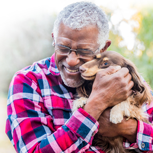 Image of man holding dog close to face and smiling